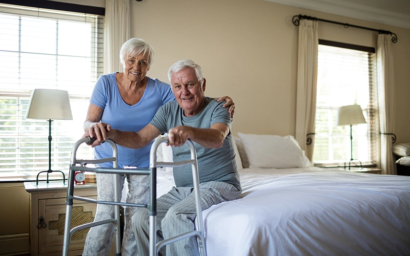man with walker and smiling wife